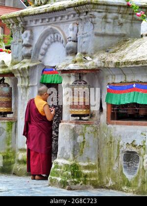 Buddhistischer Mönch, der in der Nähe von Gebetsrädern betet, Boudhanath, Kathmandu, Nepal Stockfoto