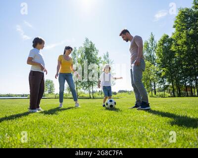 Eltern und Kinder spielen gemeinsam im Park Fußball Stockfoto