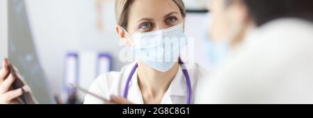 Arzt in Schutzmaske mit Röntgenaufnahme des Patienten Stockfoto