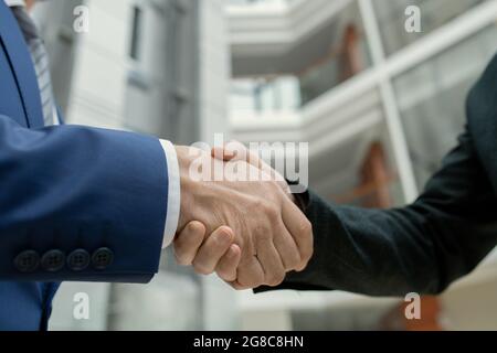 Nahaufnahme von zwei Architekten, die sich die Hände gegen das Bürogebäude schüttelten Stockfoto