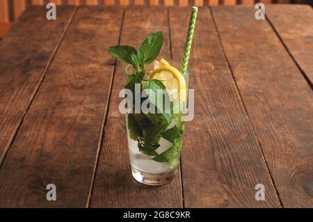 Sommer-Zitruscocktail mit Zitrone und Minze, mohito. Kalte Limonade mit Zitrone auf braunem Holztisch Stockfoto