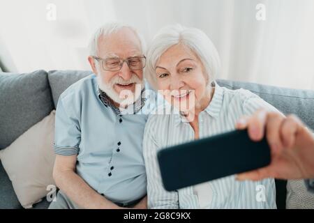 Glückliches Seniorenpaar, das Spaß hat und Fotos auf dem Handy macht, um sie online in sozialen Netzwerken zu teilen - ältere Menschen mit moderner Technologie, gran Stockfoto