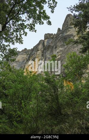 Felsen in den Bergen von unten über grüne Bäume aus nächster Nähe. Pietra di Bismantova, Italien. Wandern, Trekking, Camping, Erlebniskonzept Stockfoto