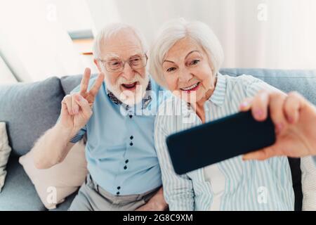 Glückliches Seniorenpaar, das Spaß hat und Fotos auf dem Handy macht, um sie online in sozialen Netzwerken zu teilen - ältere Menschen mit moderner Technologie, gran Stockfoto