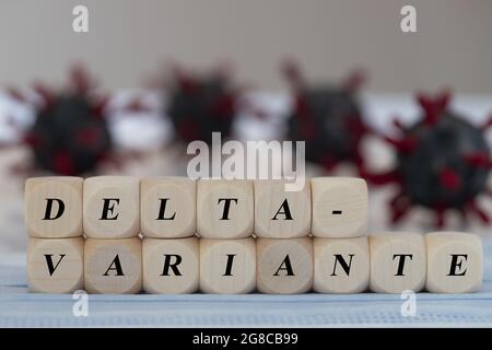 Holzwürfel mit dem deutschen Wort für Delta-Variante, Konzept für die Koronaverbreitung von Delta-Virus-Variante, Virusmodell im Hintergrund Stockfoto