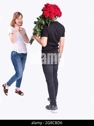 Das hübsche Mädchen ist froh, dass ihr Freund einen schönen Strauß ihrer Lieblingsblumen trägt. Stockfoto