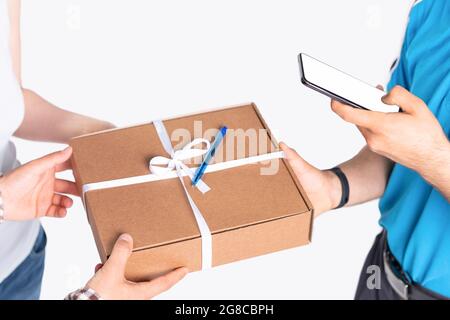 Der Kurier mit blauen Uniformmarkierungen in seinem Handy das Paket wurde für ein junges Paar pünktlich geliefert. Stockfoto
