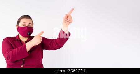 Plus Größe Mode-Modell in Casual Fashion rosa Kleidung trägt Gesichtsmaske in einer rosa Farbe zeigt die Hände nach oben. Stockfoto