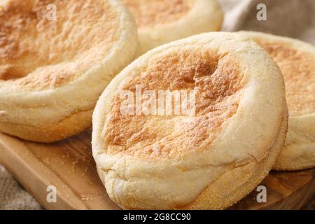 Köstliche authentische englische Muffin-Brötchen aus der Nähe auf einem Holzbrett auf dem Tisch. Horizontal Stockfoto