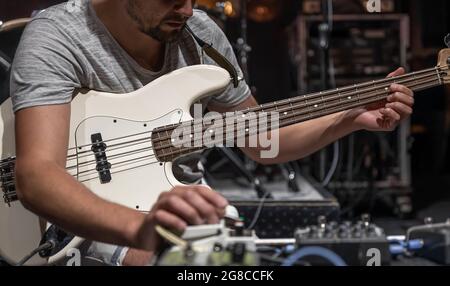 Ein männlicher Gitarrist, der auf der Bühne Audio-Verarbeitungseffekte für die Gitarre einspielt. Stockfoto