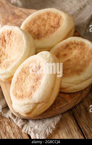 Frisch gebackene englische Muffins aus der Nähe in einem Brett auf dem Tisch. Vertikal Stockfoto