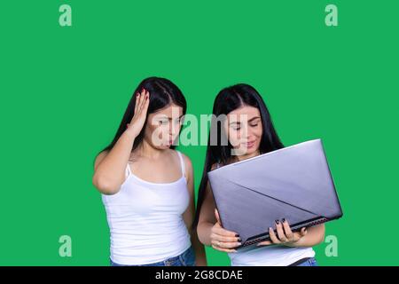 Einer der Zwillinge zeigt einem anderen etwas Interessantes auf dem Computer, der es in ihren Händen hält. Stockfoto