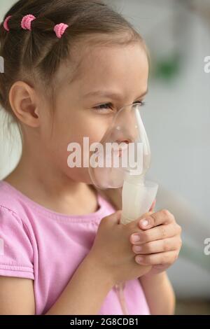 Porträt eines kranken kleinen Mädchens, das Inhalator hält Stockfoto