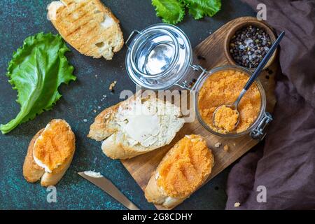 Sandwiches mit Butter und gesalzenem Kaviar auf einer Arbeitsplatte aus dunklem Stein. Draufsicht flach lay Hintergrund. Stockfoto