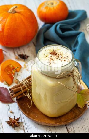 Herbstgetränk. Kürbis gewürzter Latte oder Kaffee im Glas auf einem rustikalen Holztisch. Stockfoto