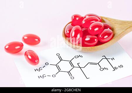 Vitamin Coenzym Q10 mit chemischer Formel auf rosa Hintergrund. Um Alterung zu verhindern. Pillen und Medikamente Stockfoto