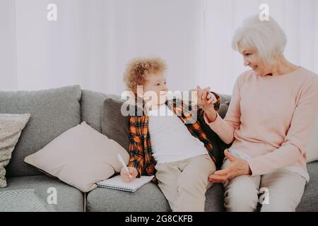 Großeltern und Enkel spielen zu Hause - Familie zu Hause, Großmutter kümmert sich um Neffen Stockfoto