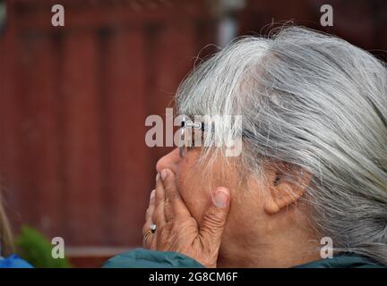 Besorgt und überraschte eine ältere Frau, die ihren Mund vor Wut bedeckte, mit Brille, grauem Haar und Kopierraum Stockfoto