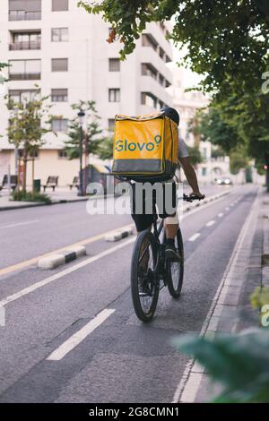 Valencia, Spanien - Juli 2021: Glovo-Fahrer, Lieferer auf einem Fahrrad, der eine Bestellung ausliefern wird. Glovo App Delivery Service Stockfoto