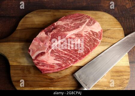 Short Rib oder Costela Premium. Schönes rohes Steak unter einem Holzbrett auf einem Holzhintergrund. Für einen brasilianischen Grill. Stockfoto