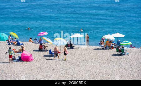 Bier, East Devon; 19. Juli 2021. Wetter in Großbritannien: Urlauber genießen den herrlichen Sonnenschein und entspannen sich am Strand und kühlen sich im blauen Meer im hübschen Fischer- und Küstendorf Beer, East Devon ab. Kredit: Celia McMahon/Alamy Live Nachrichten Stockfoto