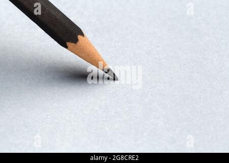 Schließen Sie den schwarzen Bleistift mit dem Strich auf grauem Papier Stockfoto