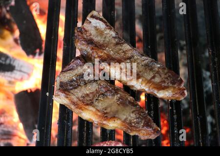 Picanha Nahaufnahme mit Grillmarkierungen auf dem Grill mit glühender Kohle auf dem Hintergrund Stockfoto