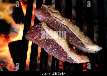 Picanha Nahaufnahme mit Grillmarkierungen auf dem Grill mit glühender Kohle auf dem Hintergrund Stockfoto
