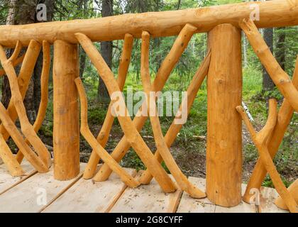 Dekorative Geländer einer hölzernen Fußgängerbrücke im Sommerpark, Hintergrundbild Stockfoto