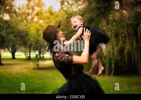 Hand in schwarzem Kleid spielt mit ihrer Tochter in schwarzem Kleid. Stockfoto