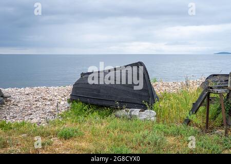 Ein altes Holzboot an der Küste. Bild von der Ostsee. Blauer Himmel und Meer im Hintergrund. Stockfoto
