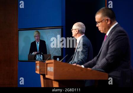 (Von links nach rechts) Premierminister Boris Johnson erscheint auf einem Bildschirm von Chequers, dem Landhaus des amtierenden britischen Premierministers, wo er sich selbst isoliert, der wissenschaftliche Chefberater Sir Patrick Vallance und der stellvertretende leitende medizinische Offizier für England Professor Jonathan Van Tam, während einer Medienbesprechung in der Downing Street, London, über das Coronavirus (Covid-19). Bilddatum: Montag, 19. Juli 2021. Stockfoto