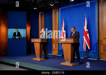 (Von links nach rechts) Premierminister Boris Johnson erscheint auf einem Bildschirm von Chequers, dem Landhaus des amtierenden britischen Premierministers, wo er sich selbst isoliert, der wissenschaftliche Chefberater Sir Patrick Vallance und der stellvertretende leitende medizinische Offizier für England Professor Jonathan Van Tam, während einer Medienbesprechung in der Downing Street, London, über das Coronavirus (Covid-19). Bilddatum: Montag, 19. Juli 2021. Stockfoto