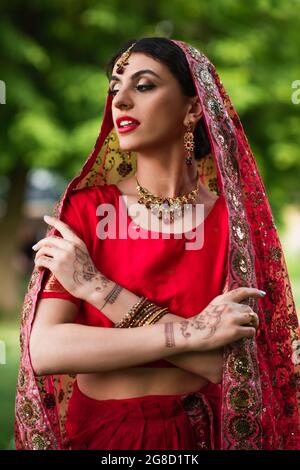 Junge indische Braut in rotem Sari und Kopftuch mit Ornament Stockfoto