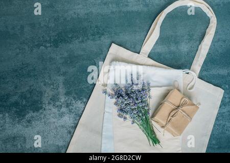Lavendel-Bouquet, Geschenkbox, Öko-Taschen auf Betongrund. Draufsicht flach liegend, umweltfreundlich und ohne Abfall Stockfoto