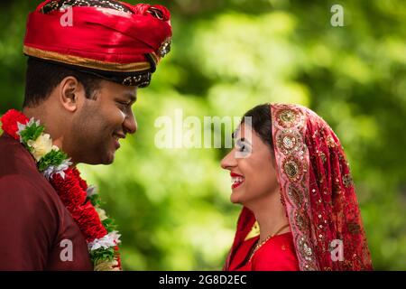 Seitenansicht des glücklichen indischen Bräutigams und der Braut, die einander anschauten Stockfoto