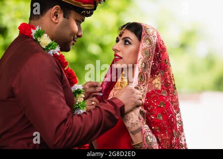 indischer Mann, der das Kopftuch auf der Braut in Sari anpasst Stockfoto