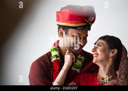 Glückliches indisches Ehepaar aus Mann und Frau in traditioneller Kleidung, die sich auf Weiß anguckt Stockfoto