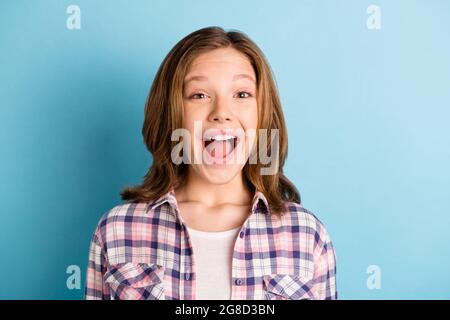 Foto von beeindruckt charmante Schulmädchen tragen karierte Hemd offenen Mund isoliert blaue Farbe Hintergrund Stockfoto