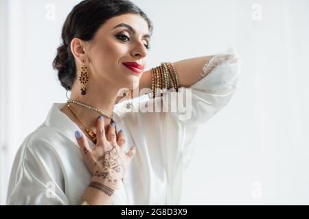 Glückliche junge indische Braut trägt Halskette auf weiß Stockfoto
