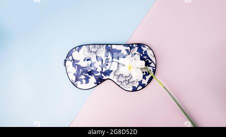 Schöne Seidenschlafmaske für Augen mit Blumenmuster und weißen Narzissen oder Narzissen auf rosa blauem Hintergrund, Panorama Stockfoto