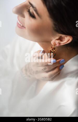 High-Angle-Ansicht der glücklichen indischen Braut tragen Ohrring, während immer bereit für die Hochzeit isoliert auf weiß Stockfoto