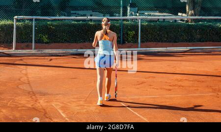 Ankara, Türkei-7. Juli 2013: Junge Tennisspielerin, die während des Trainings auf dem Sandplatz im Sommer zur Grundlinie geht. Individuelles Sportkonzept. Stockfoto