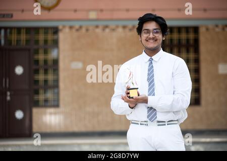 Portrait eines glücklichen Studenten mit Preis in der Hand, der Erfolg feiert Stockfoto