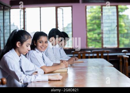 Frontseitiges Porträt einer jungen Schülerin in der Bibliothek mit negativem Raum Stockfoto