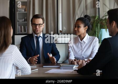 Selbstbewusster männlicher Unternehmensleiter, der beim Briefing mit dem Team spricht Stockfoto