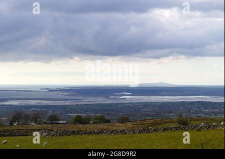 Walisische Landschaft, von Anglesey von der Halbinsel Llyn aus gesehen. Dramatischer stürmischer Himmel an einem Frühlingstag. Blick auf die Menai Straight und den Holyhead Mountain Stockfoto