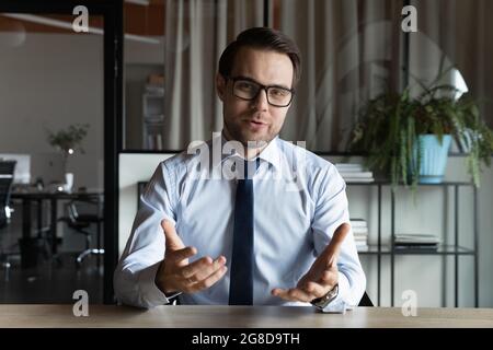 Positiver Business-Profi im Anzug und Brille beim Blick auf die Webcam Stockfoto