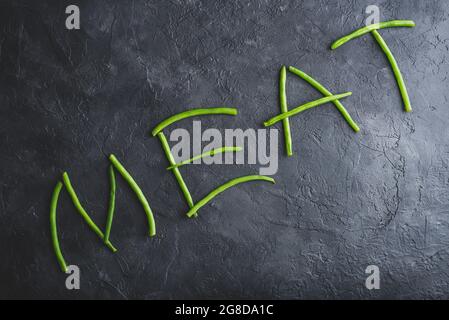 Wort Fleisch in frischen Pods of Green Beans geschrieben Auf dunklem Beton-Hintergrund Stockfoto