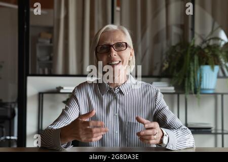 Glückliche reife Lehrerin, Tutorin, Trainerin mit Brille beim Webinar Stockfoto